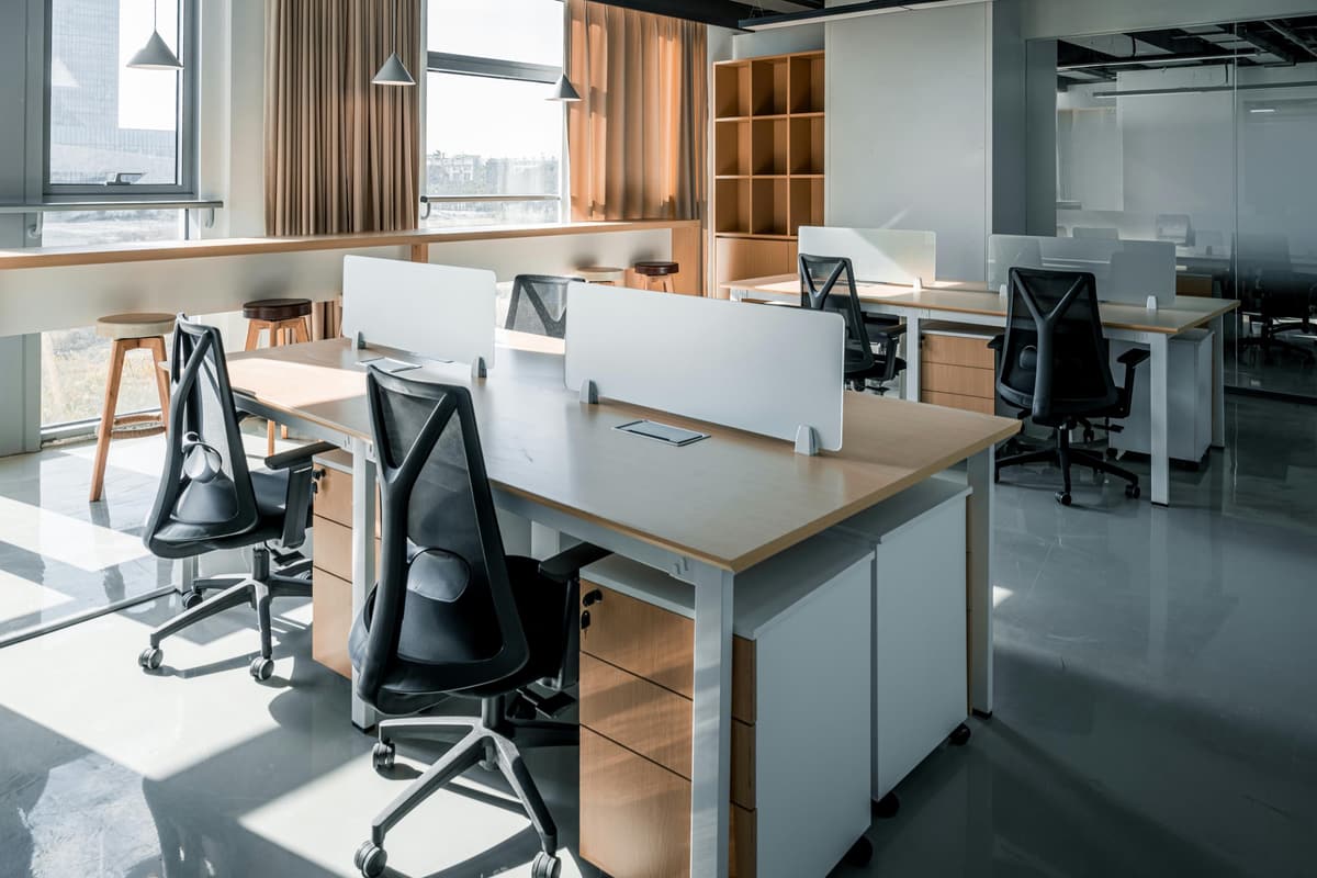 An open-plan office with rows of desks and black task chairs