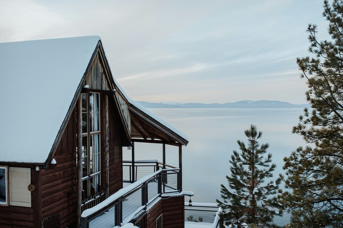 A snow-covered A-frame cabin overlooking Lake Tahoe