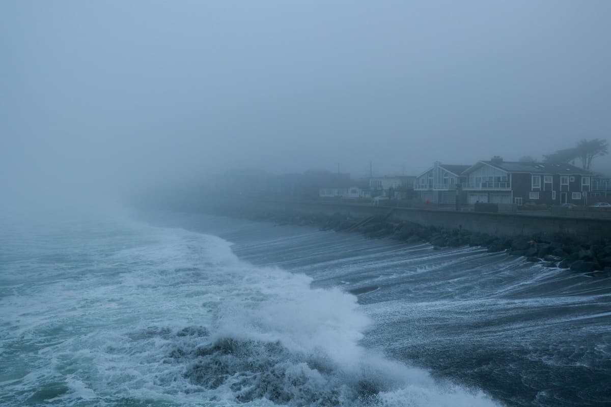 Fog rolling in over waves and coastal homes on the Peninsula
