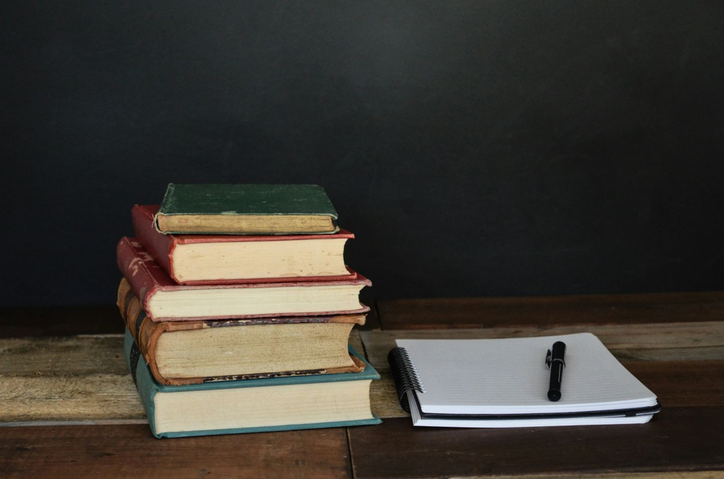 A stack of books beside a notebook and pen, representing ongoing education